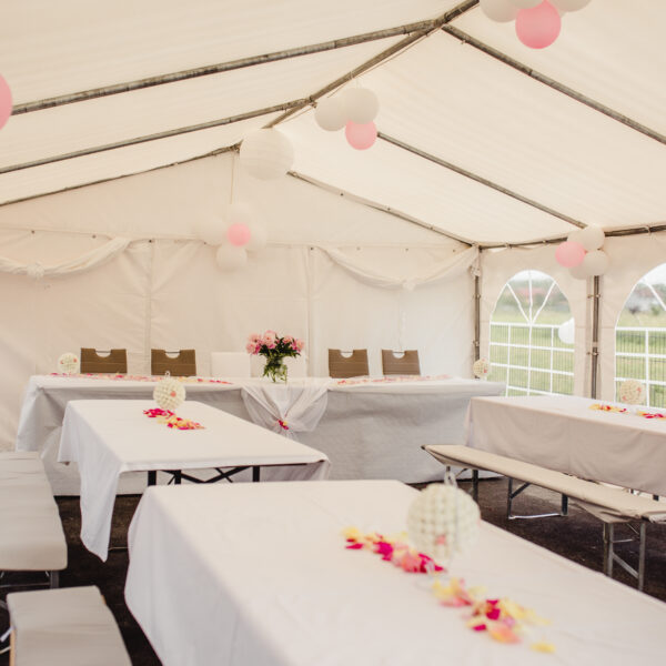 The,Tables,And,Benches,In,A,Wedding,Tent,Decorated,With